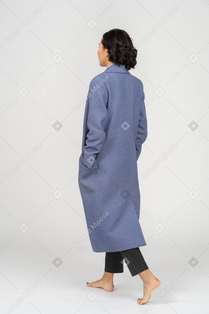 Punto di vista posteriore della donna in cappotto che cammina a piedi nudi