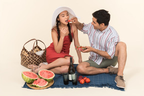Interracial couple having picnic and man giving strawberries to a girl