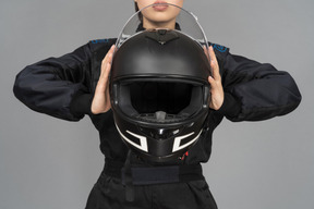 A woman holding a black helmet at a chest level
