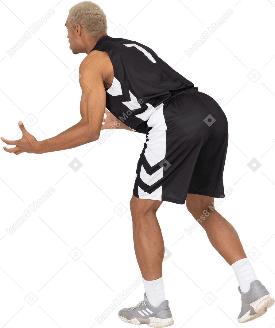 Vista posterior de tres cuartos de un joven jugador de baloncesto masculino cuestionando inclinándose hacia adelante
