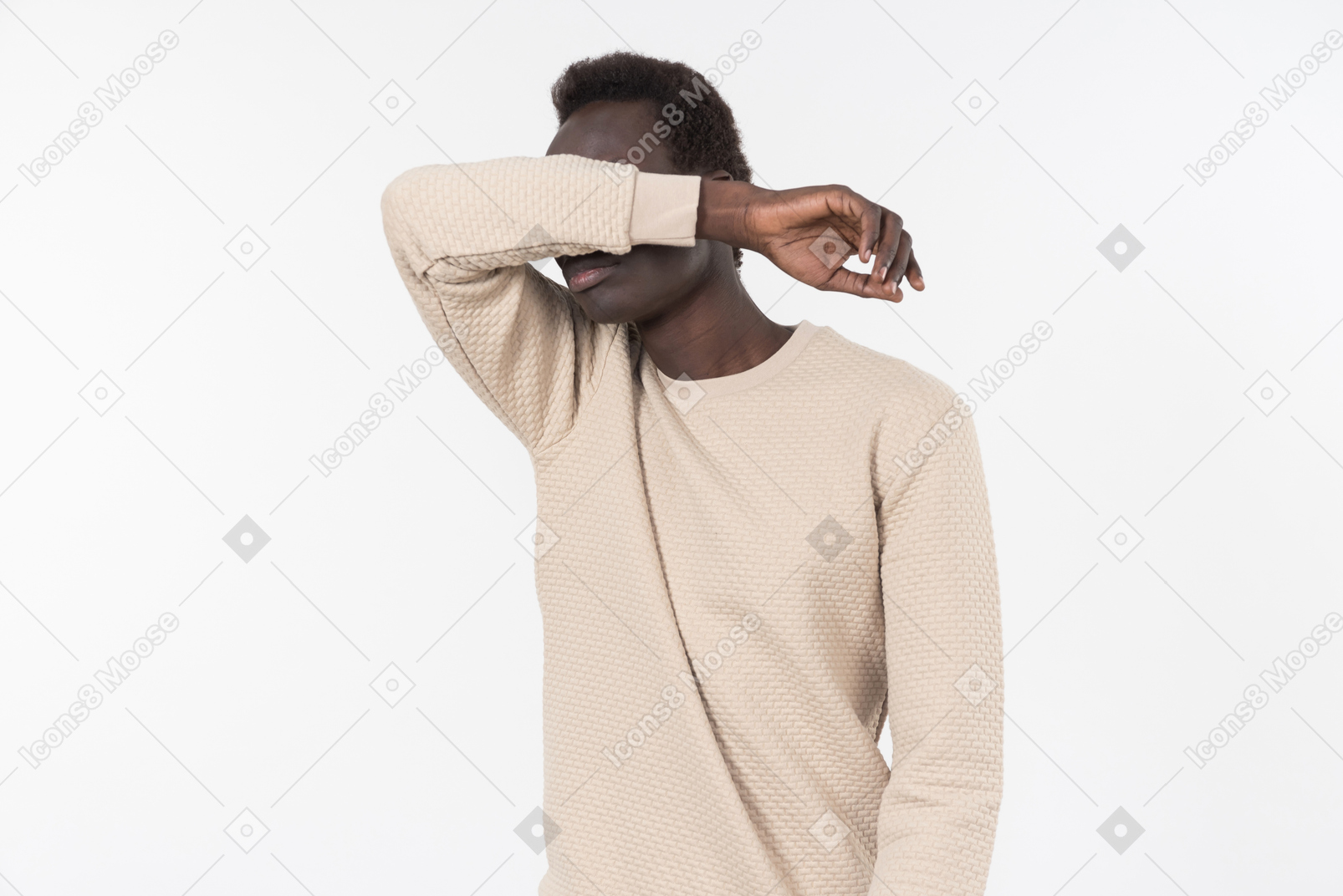 Un joven negro en un suéter gris de pie solo sobre el fondo blanco.