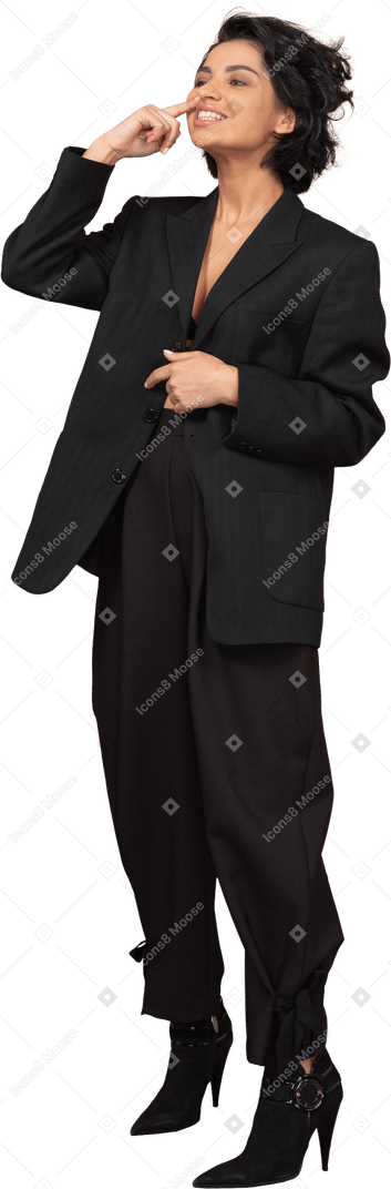 Vista de tres cuartos de una divertida empresaria en un traje negro tocando su nariz