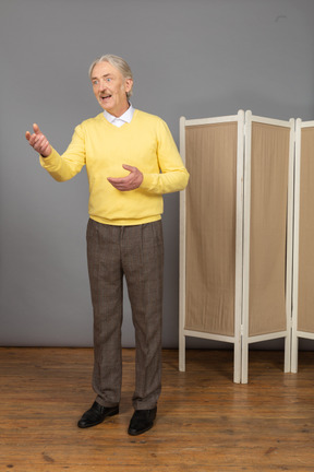 Vue de trois quarts d'un vieil homme expliquant quelque chose en gesticulant