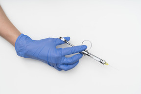 A hand in blue glove holding a syringe