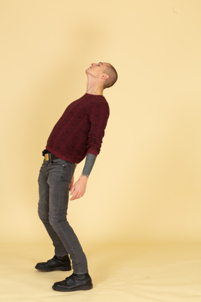 Side view of a young man in red pullover leaning back