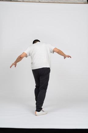 Back view of a man in casual clothes walking with outstretched arms