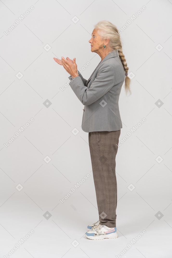 Vista lateral de una anciana en traje explicando algo