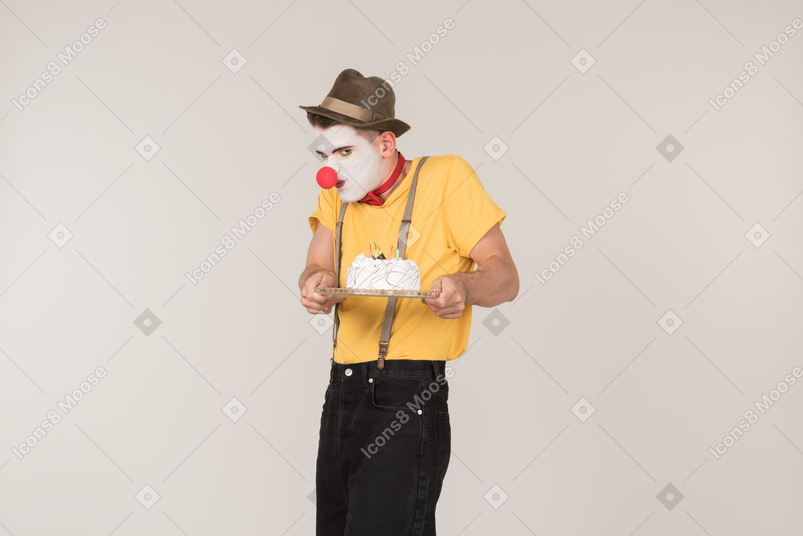 Male clown tasting a cake he's holding