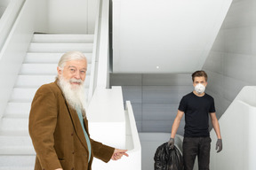 An old man and a young man in face mask on the stair landing