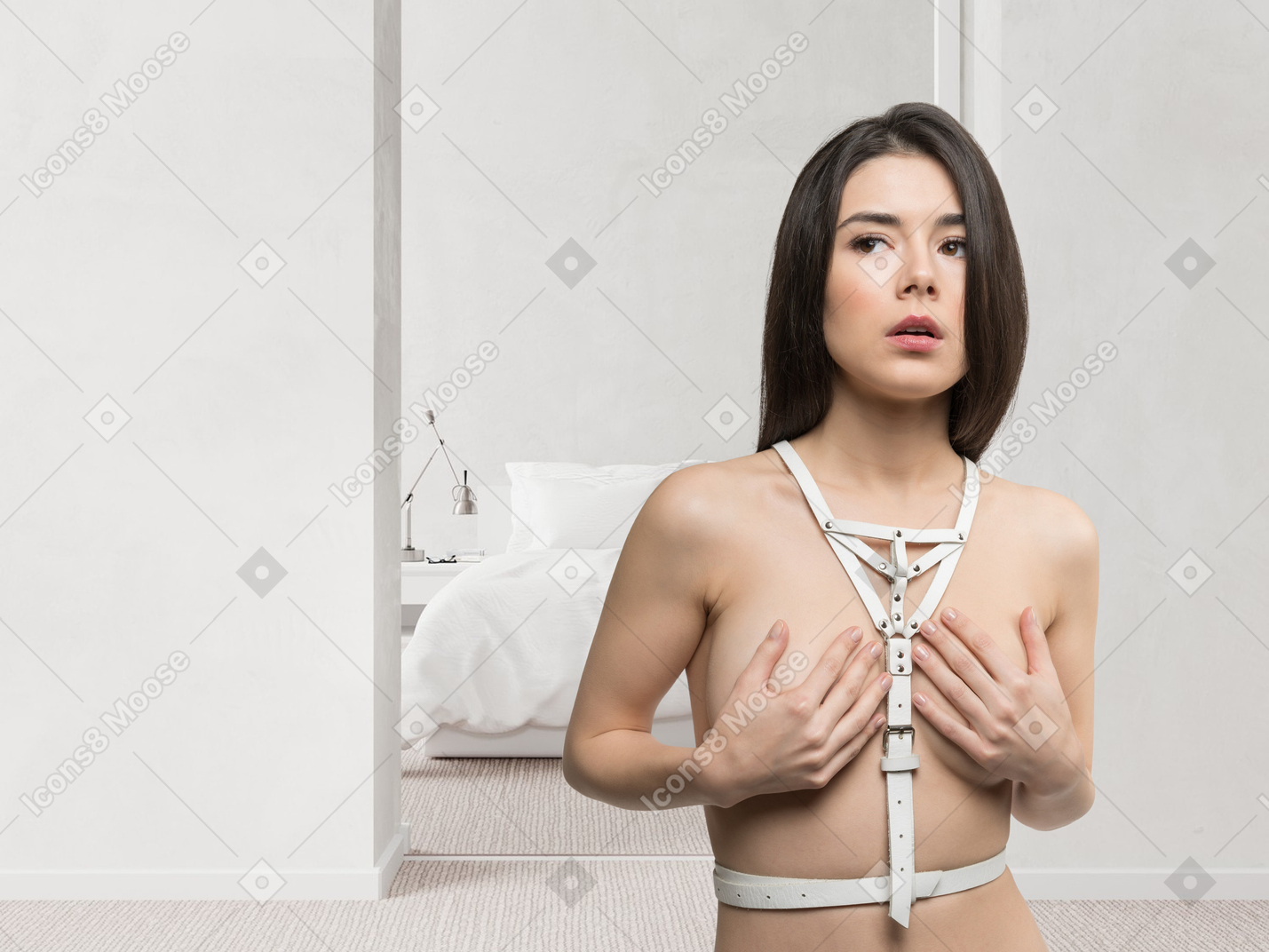 A woman in a white leather body harness with her hands on her chest