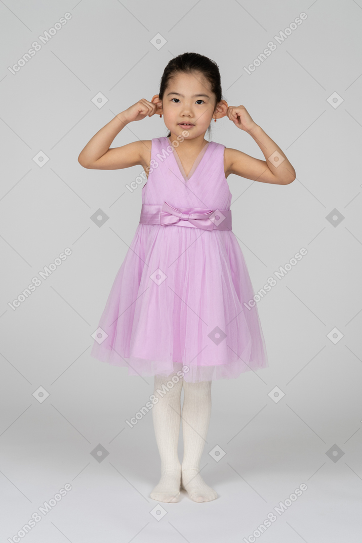 Bambina in abito rosa tirando le orecchie