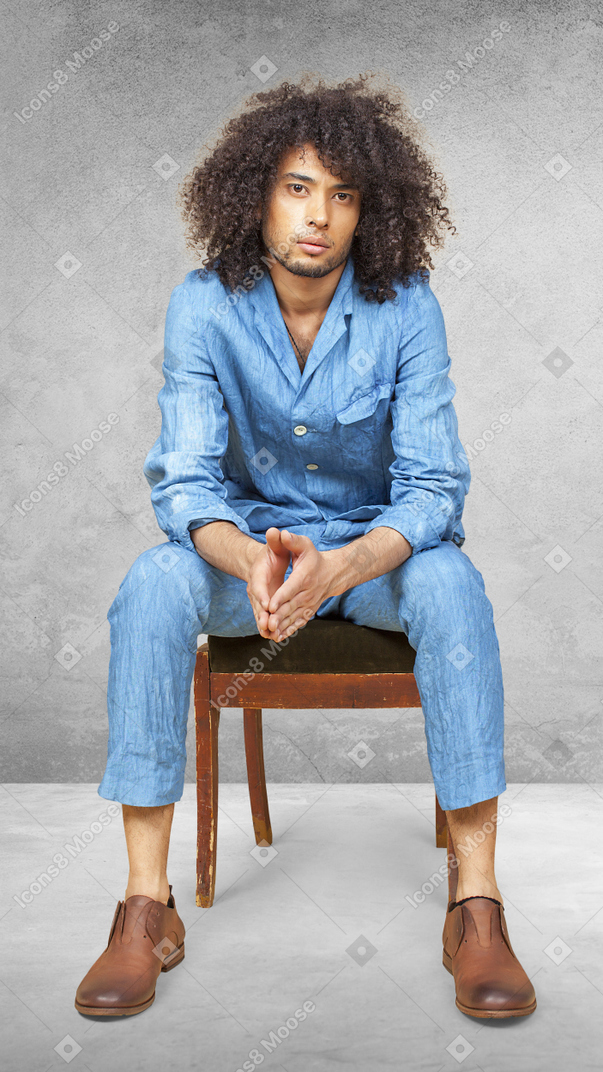 Junger mann in einem anzug, der auf einem stuhl sitzt