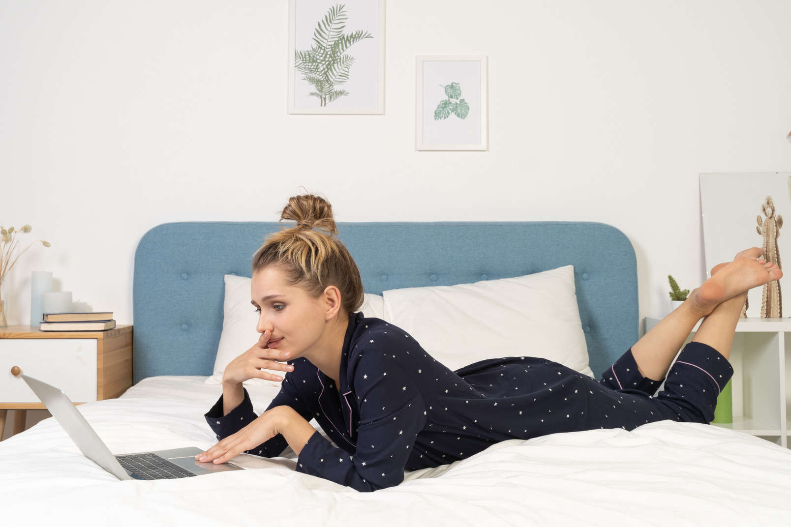 Side view of a young female laying in bed with her laptop