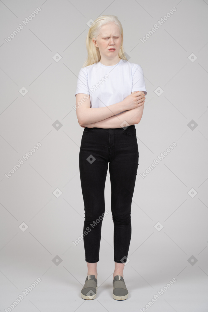 Standing young girl touching her upper arm