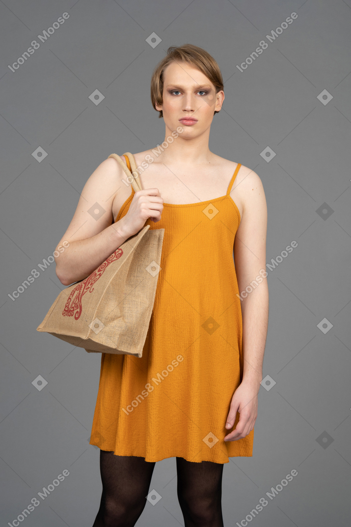 Retrato de uma jovem transgênero em bolsa de transporte de vestido laranja