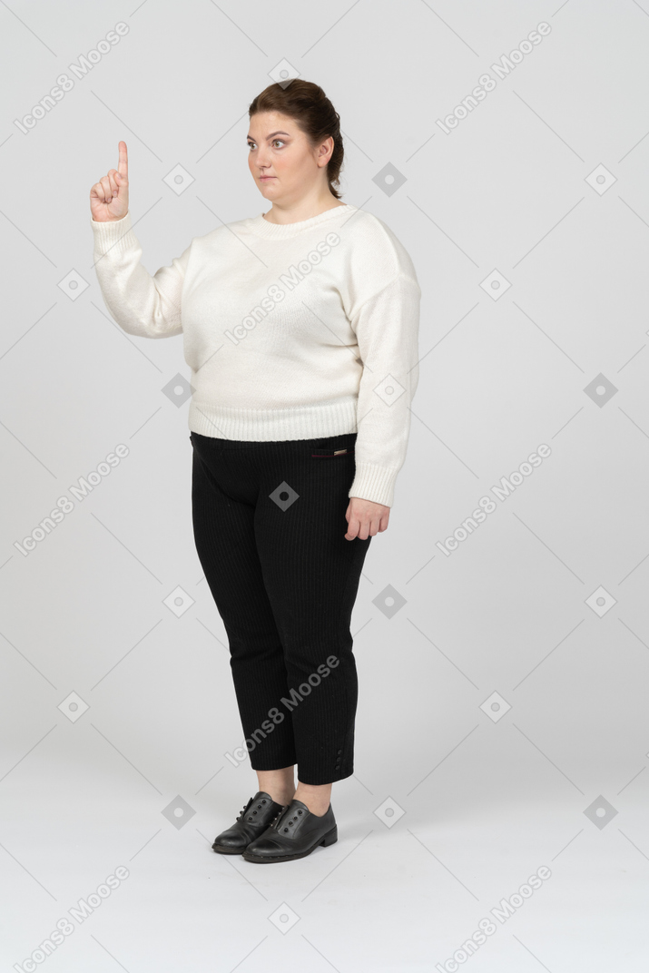 Mulher de tamanho grande em roupas casuais apontando para cima com um dedo