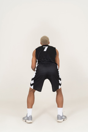 Back view of a young male basketball player holding a ball