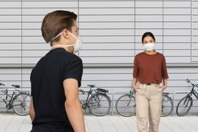 A woman wearing a face mask standing next to a man