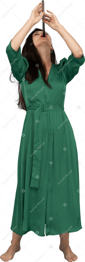 Vue de face d'une jeune femme en robe verte jouant de la flûte en se penchant en arrière
