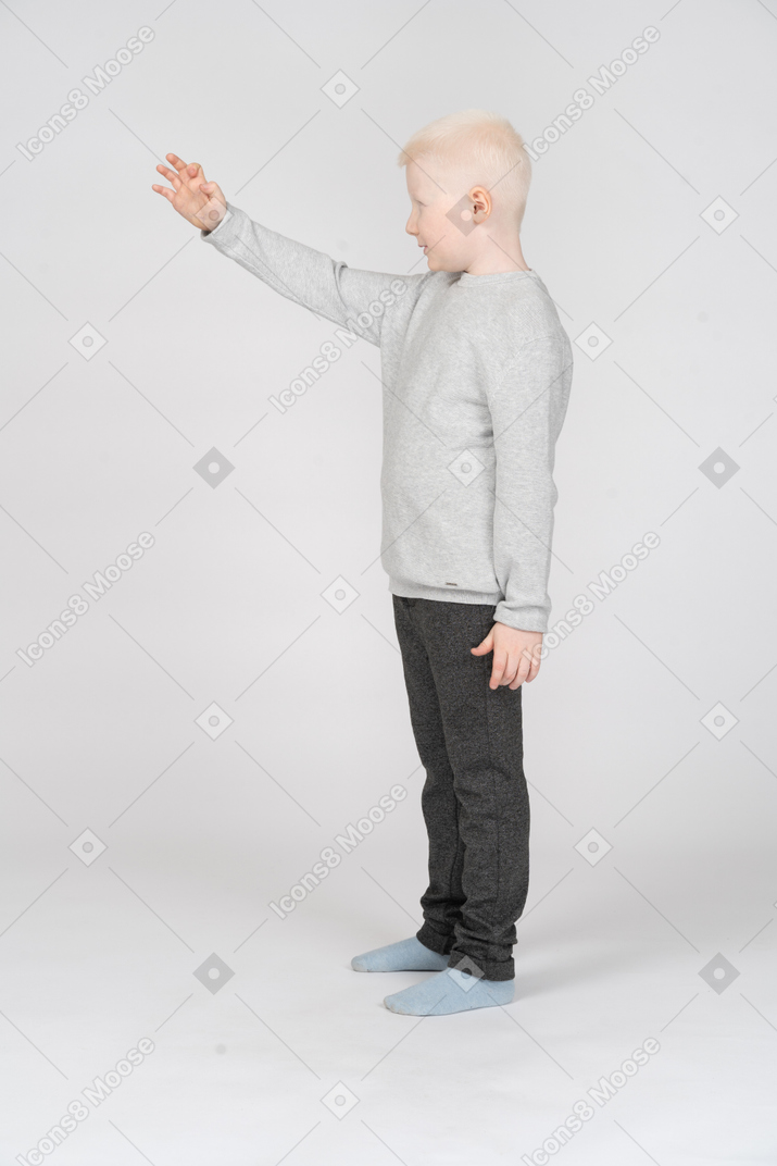 Side view of a boy reaching out for something
