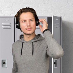A man wearing headphones standing in front of lockers
