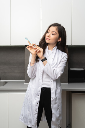 Front view of a female dentist looking attentively at the toothbrush