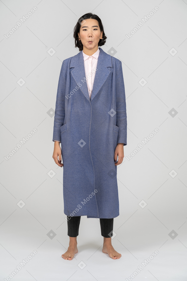 Vista frontal de una mujer con abrigo azul haciendo una cara tonta