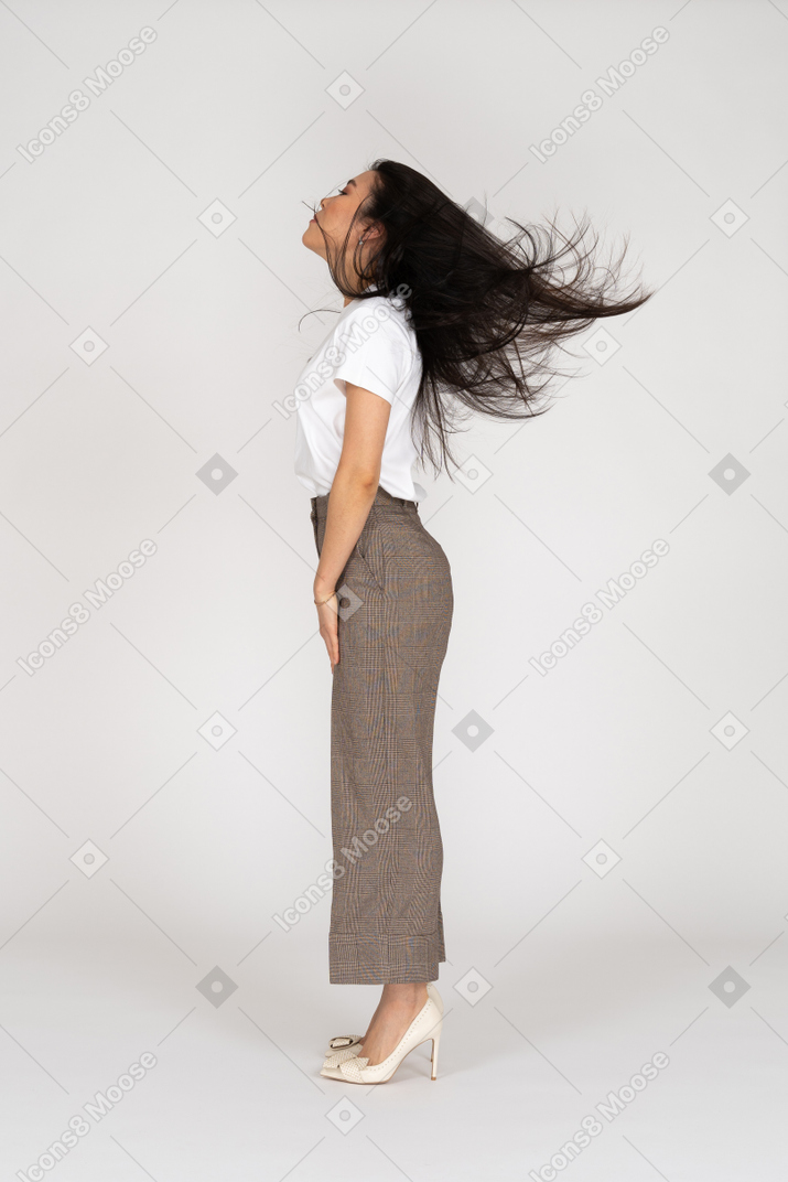 一位年轻的女士，穿着马裤和凌乱的头发的t恤的侧视图