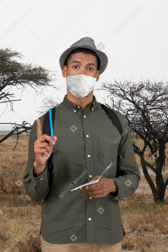 Man holding pen and notepad in nature