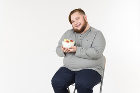 Sonriente hombre grande con plato de ensalada