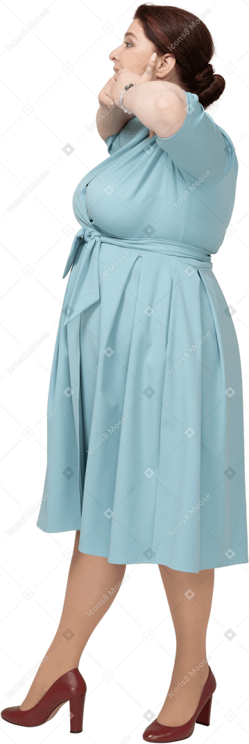 Side view of a woman in blue dress touching mouth