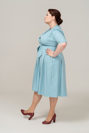 一个身着蓝色裙子、双手叉腰的女人的侧视图