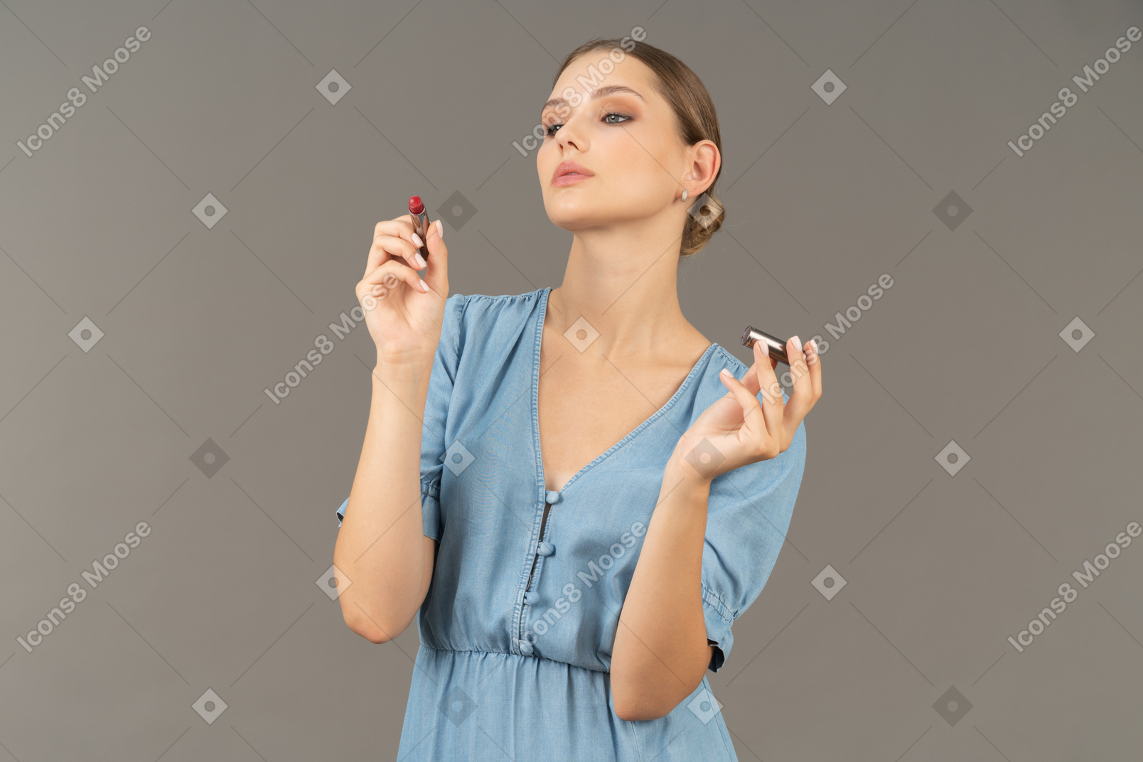 Vista frontale di una giovane donna in abito blu con in mano un rossetto