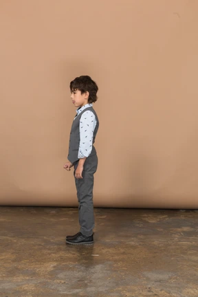 Cute boy in grey suit standing in profile