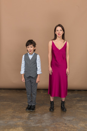 Vista frontal de um menino e uma mulher sorrindo com um vestido vermelho