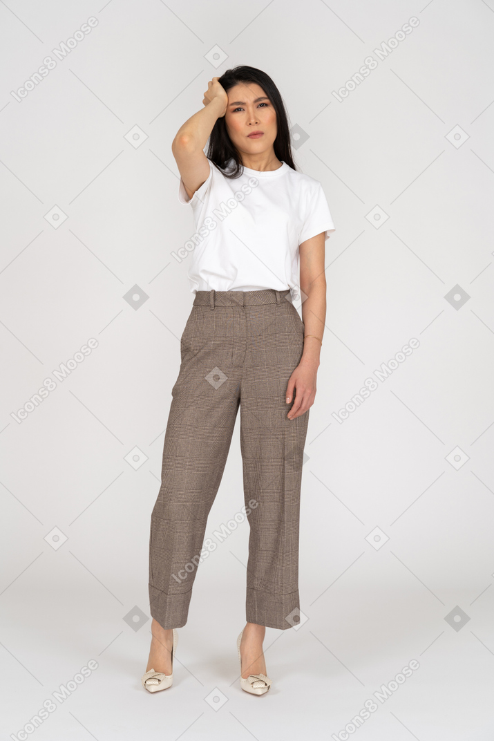 Front view of a tired young lady in breeches and t-shirt touching her head