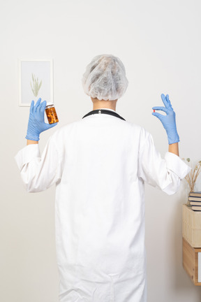 Back view of a young female doctor choosing between pills