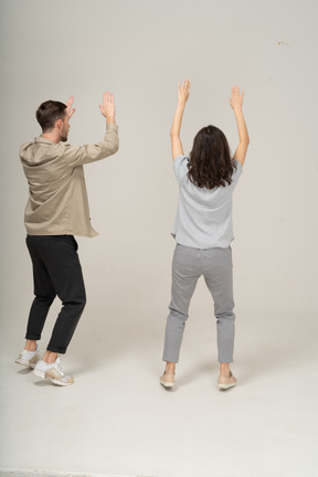 Back view of young man and woman with raised hands