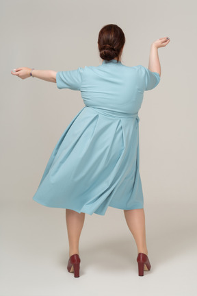 Vista posteriore di una donna in abito blu che balla