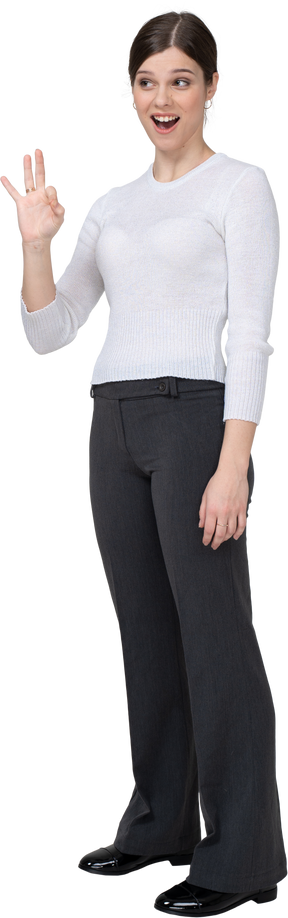 Three-quarter view of a young woman in office clothing showing ok sign