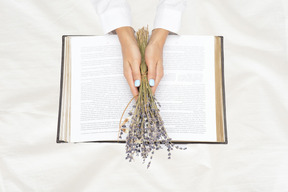 A woman is holding a book and flowers