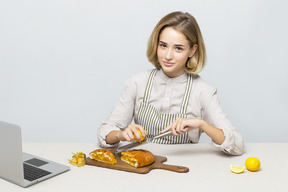 Ragazza attraente che cucina una torta al limone mentre guarda video online