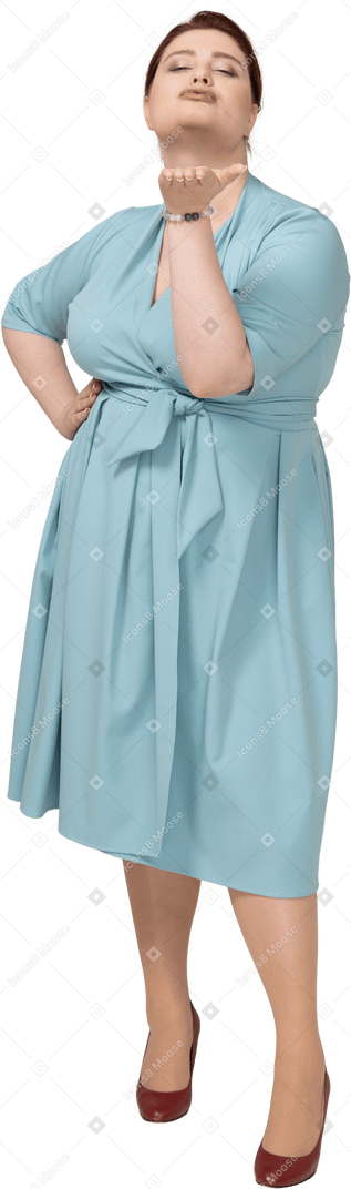 Vista frontale di una donna in abito blu che soffia un bacio