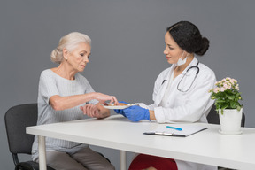 Doctora ofreciendo a su paciente anciano algunas galletas