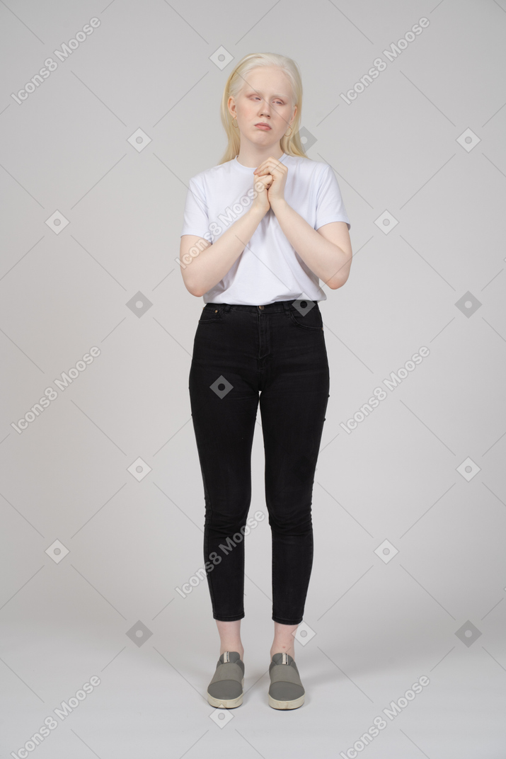 Mulher chateada em roupas casuais em pé com as mãos postas
