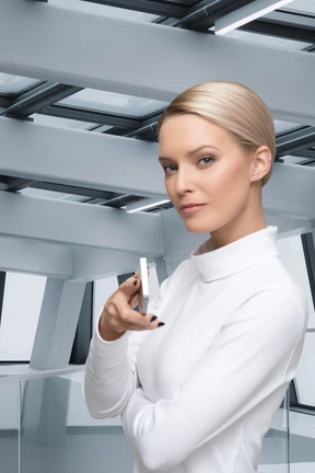 A woman in a white shirt is holding a cell phone