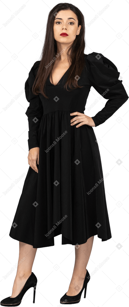 Dreiviertelansicht einer jungen dame in einem schwarzen kleid, das hand auf hüfte legt