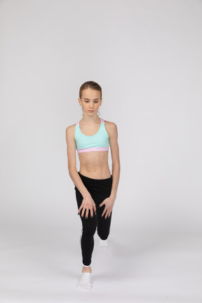 Vue de face d'une adolescente dans un vêtement de sport faisant une fente