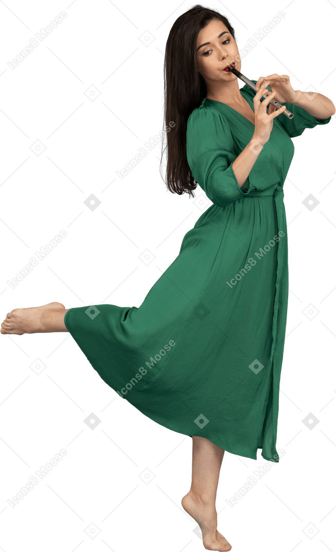 Vista lateral de uma jovem descalça de vestido verde tocando flauta