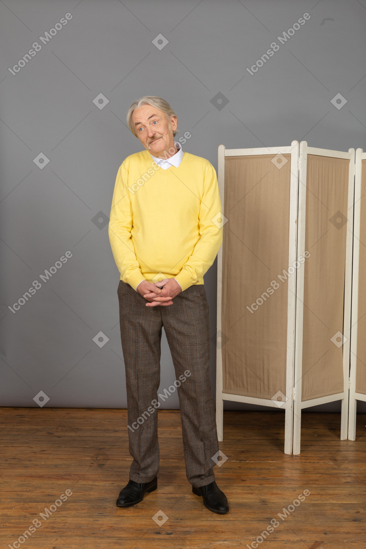 Vista frontale di un uomo anziano sorridente timido che osserva da parte